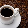 Uma xícara de café sobre vários grãos da bebida. Tomar café.
