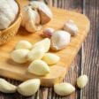 Dentes e cabeças de alho sobre uma superfície. Falando sobre os benefícios de comer alho antes de dormir.